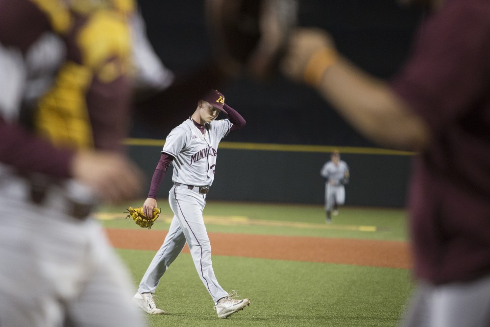 Pitcher Max Meyer walks off the field as his teammates fist bump to his successful inning during the game against UCLA on Saturday, June 2, 2018 at Siebert Field. The Gophers won 3-2.